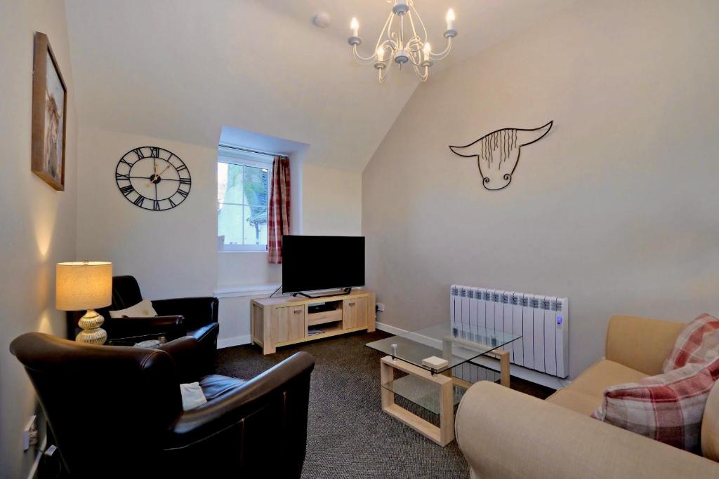 a living room with a couch and a tv at Douglas House Apartments in Nairn