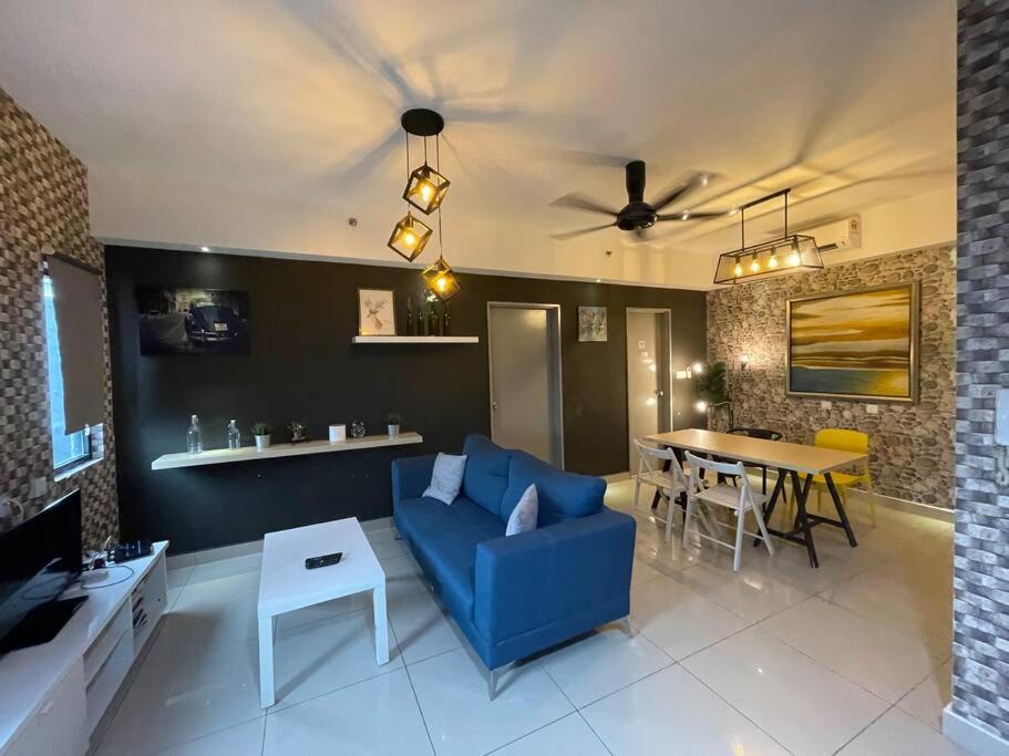 een woonkamer met een blauwe bank en een tafel bij Stylish 2-bedroom Hyve Soho Suites Near MRT in Cyberjaya