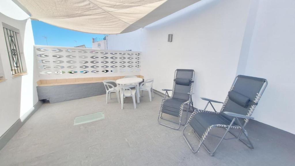 een kamer met stoelen, een tafel en een muur bij APARTAMENTO CÁDIZ TERRAZA - Pleno Casco Histórico in Cádiz