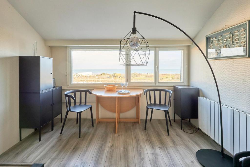 une cuisine avec une table et des chaises dans une pièce dans l'établissement Le Répit - Vue port à 200m de la plage, à Courseulles-sur-Mer