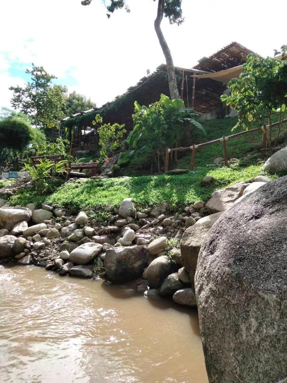 a river with rocks in front of a house at Lhong Chiang Dao Glamping หลงเชียงดาว in Chiang Dao
