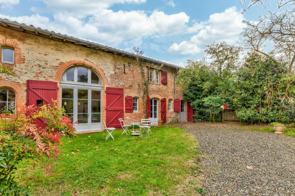 uma casa de tijolos com portas vermelhas e um quintal em La Fourragère - Maison pour 5 