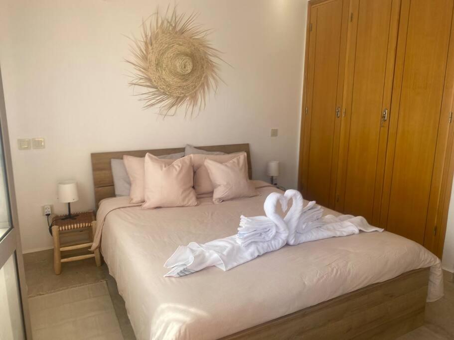Schlafzimmer mit einem Bett mit weißer Bettwäsche und Kissen in der Unterkunft Bel appart wifi balcon et parking Marrakech centre in Marrakesch