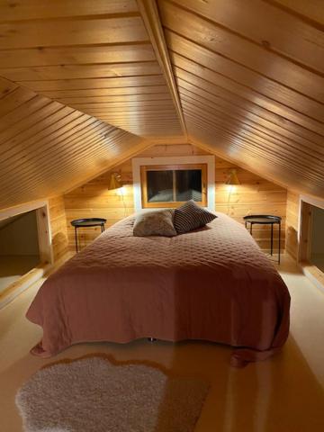 a large bed in a room with a wooden ceiling at Lomanaamanka Naava-Cottage / Naava-hirsimökki in Syöte