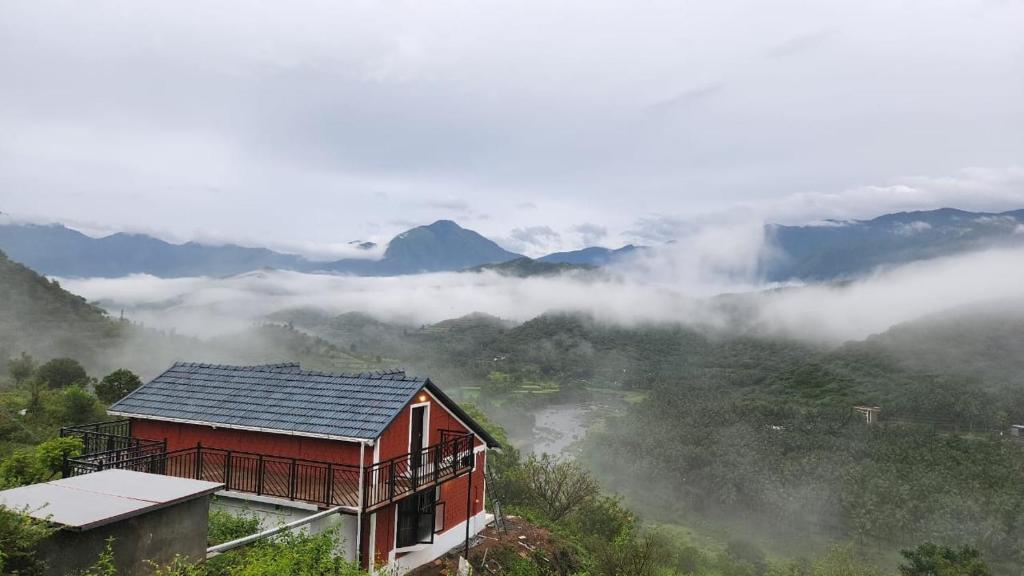 una casa en una colina con niebla en las montañas en Mistymout Homestay, en Attappādi