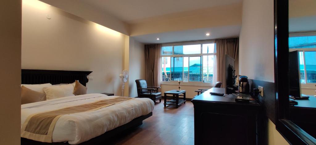 een slaapkamer met een bed, een bureau en een raam bij HOTEL RENDEZVOUS in Gangtok