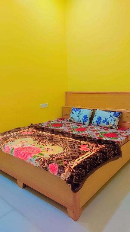 Cama en habitación con pared amarilla en laxmi homestay en Khajurāho