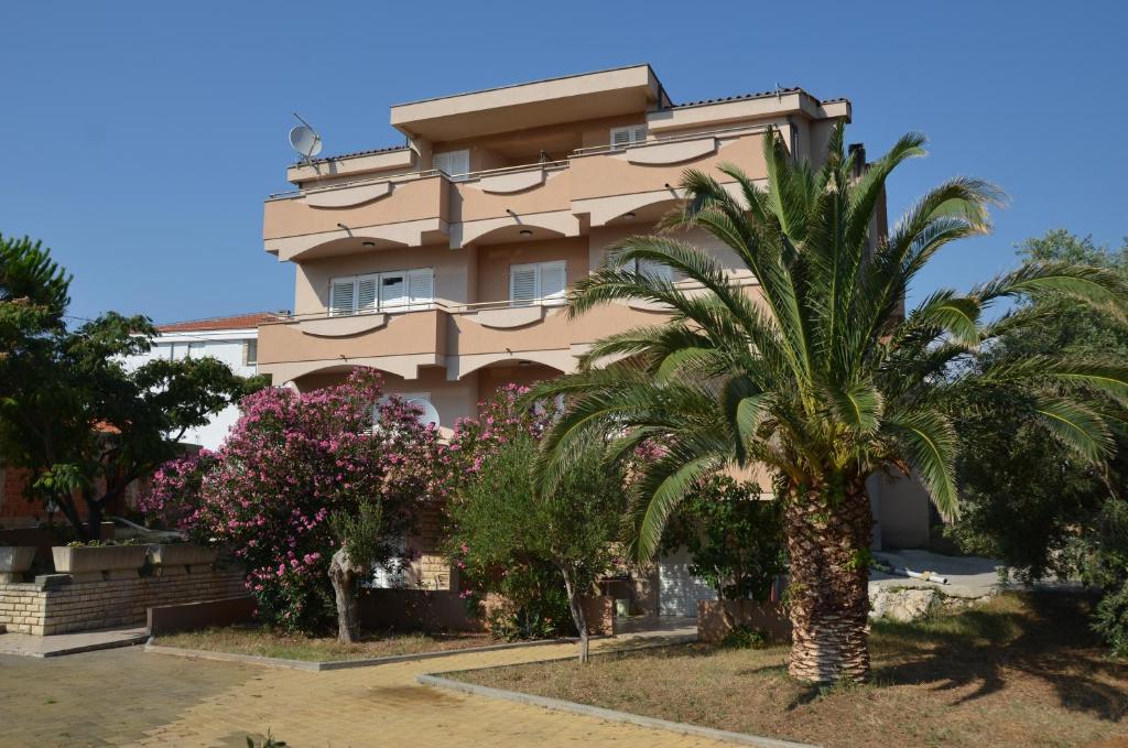 a building with palm trees in front of it at Apartments Toma in Novalja