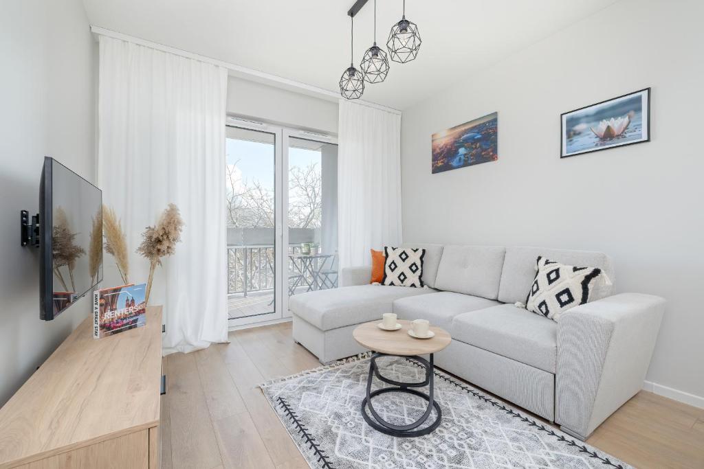 Sala de estar blanca con sofá y mesa en Bright Apartment Park Lotników Near Tauron Arena Kraków by Renters, en Cracovia