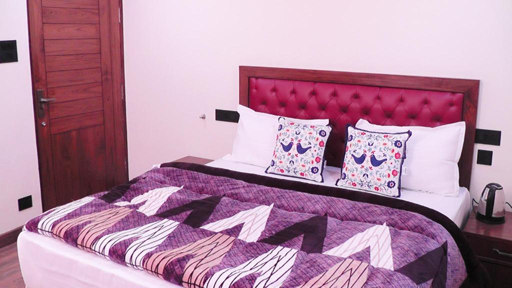 a bedroom with a bed with a purple comforter and pillows at Hotel Jakhu Heights in Shimla