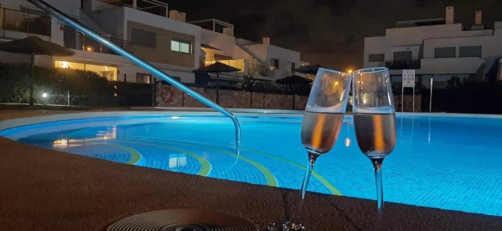 two wine glasses sitting next to a swimming pool at night at Nuestro Sueño in Orihuela Costa