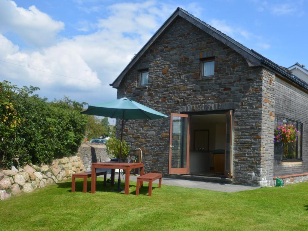 a stone house with a table and benches and an umbrella at 2 Bed in Gower 40481 in Dunvant