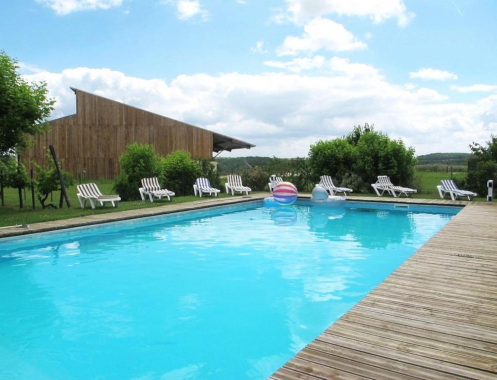 een groot zwembad met stoelen en een houten terras bij Maison contemporaine pour 12 personnes in La Sauvetat-de-Savères