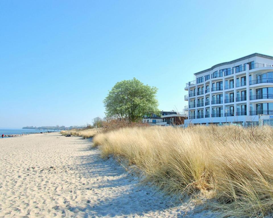 a building on the beach next to a sandy beach at SeeHuus Lifestyle Hotel in Timmendorfer Strand