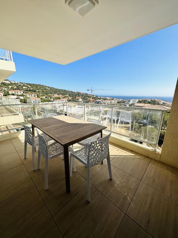 une table et des chaises sur un balcon avec vue dans l'établissement Bel appartement neuf vue mer, à LʼÎle-Rousse
