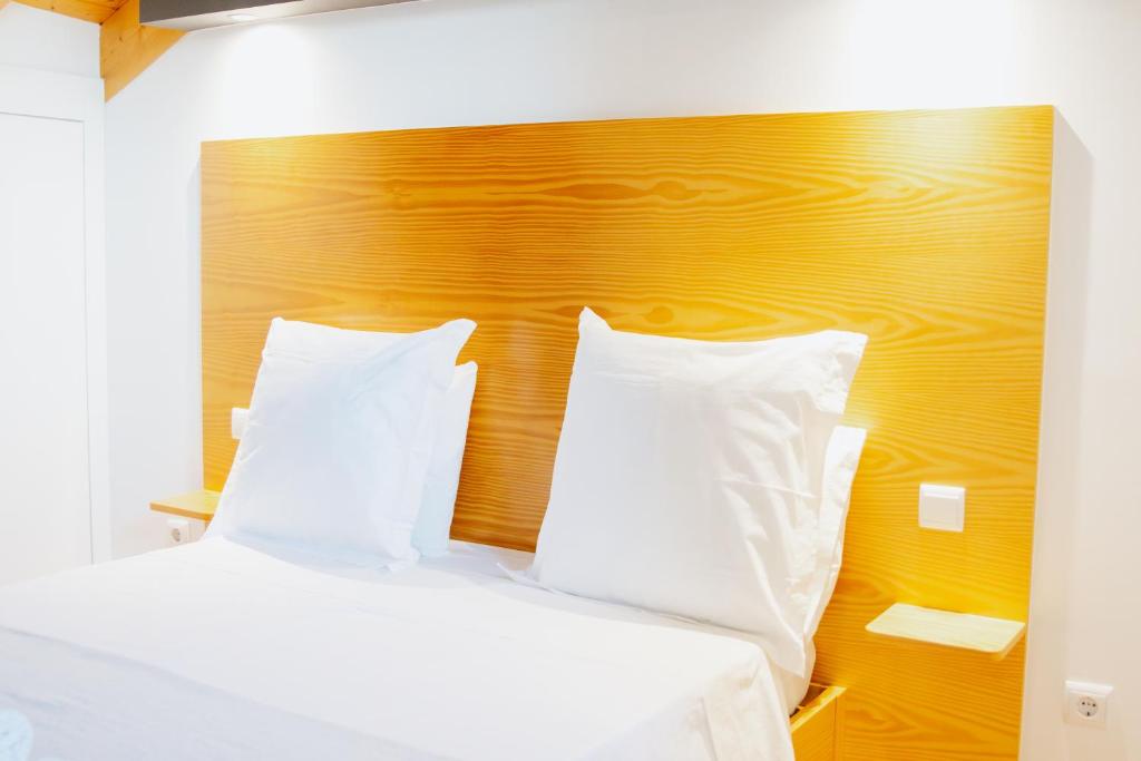 a bed with white pillows and a wooden headboard at Casa Luís de Camões - Boutique & Literary House in Santar