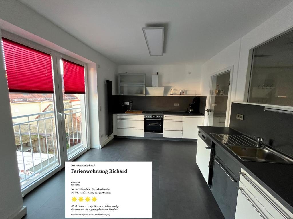 a kitchen with white cabinets and black counter tops at Ferienwohnung Richard in Zittau