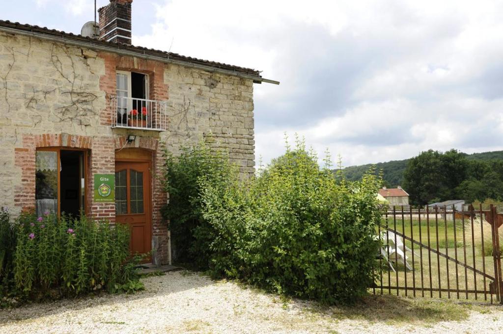 una vieja casa de piedra con una puerta y una valla en Saint-malachie en Longchamp-sur-Aujon