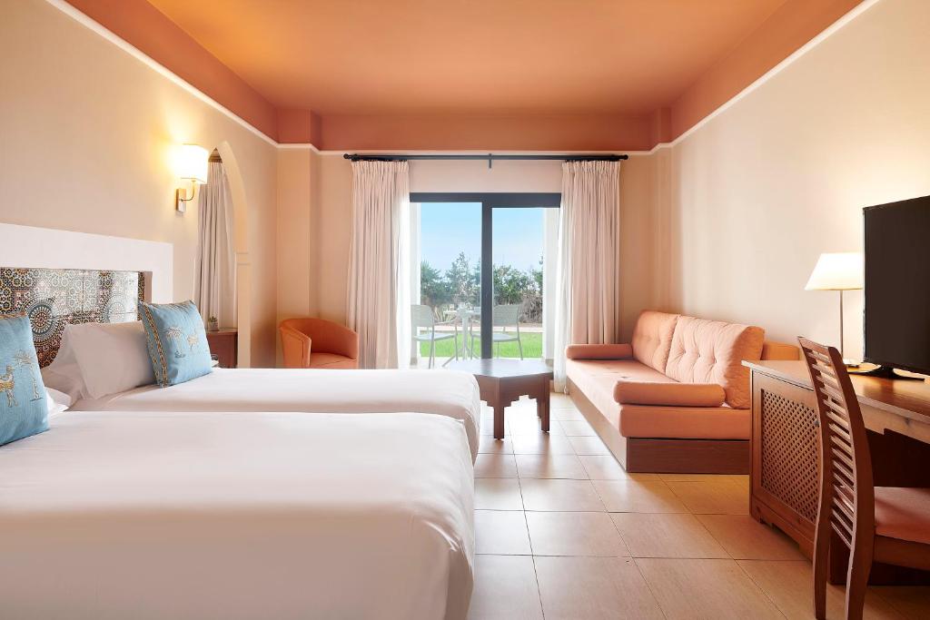 a hotel room with two beds and a couch at Iberostar Waves Saidia in Saidia 