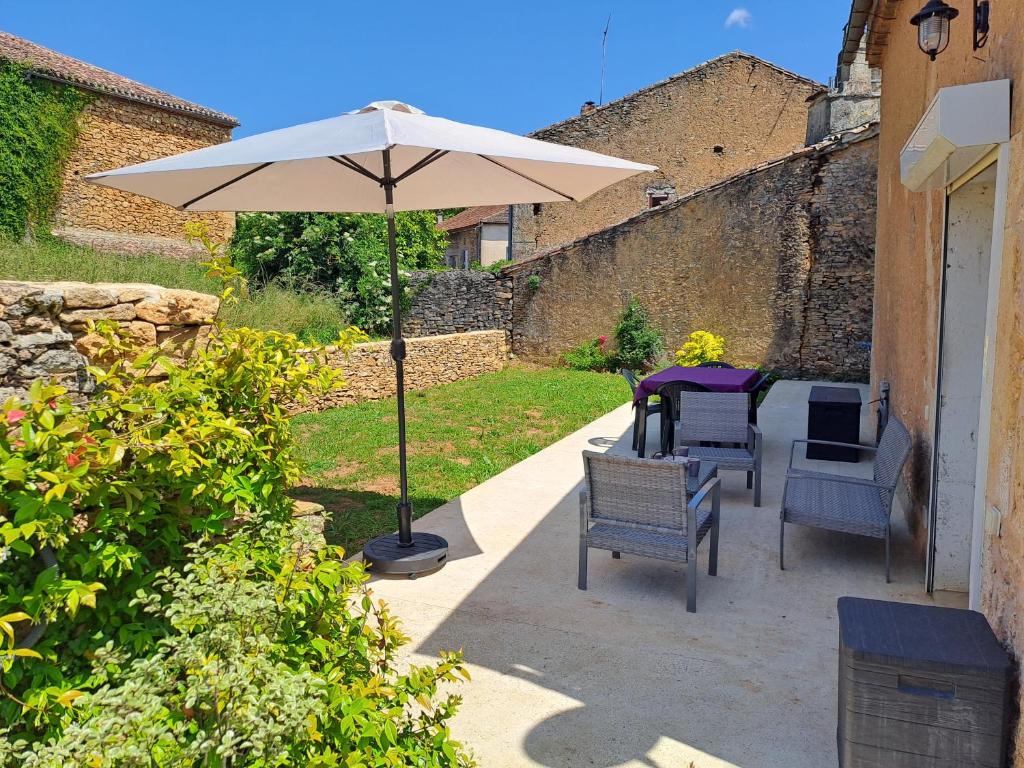 einen Tisch und Stühle unter einem Sonnenschirm auf einer Terrasse in der Unterkunft Maison de village proche Dordogne in Lacapelle-Biron