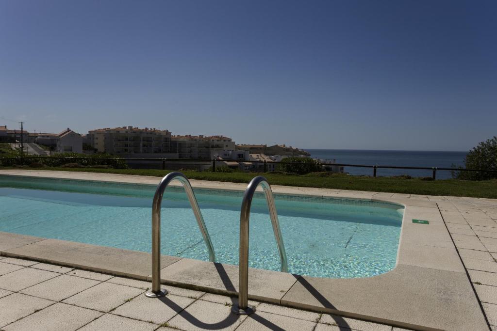 a swimming pool with two metal rails next to the water at Blue Beach by ACasaDasCasas in Ericeira