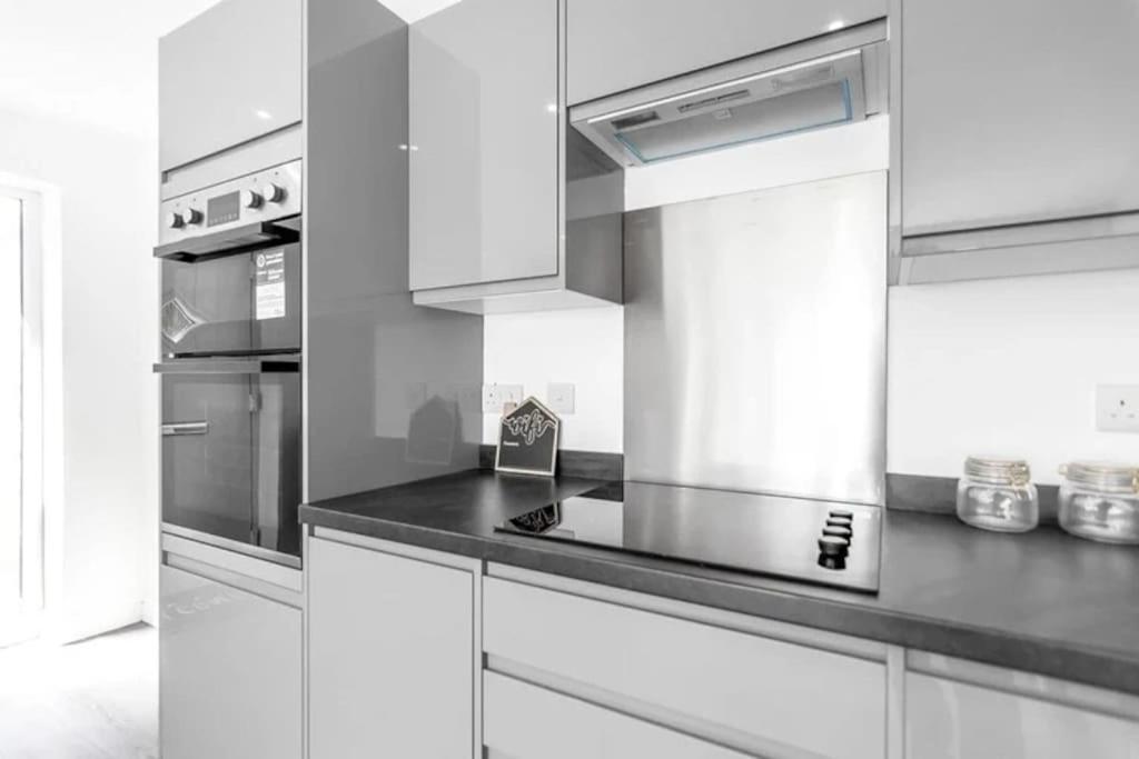 a kitchen with white cabinets and a stove top oven at Amazing bungalow with hot tub in Lessingham