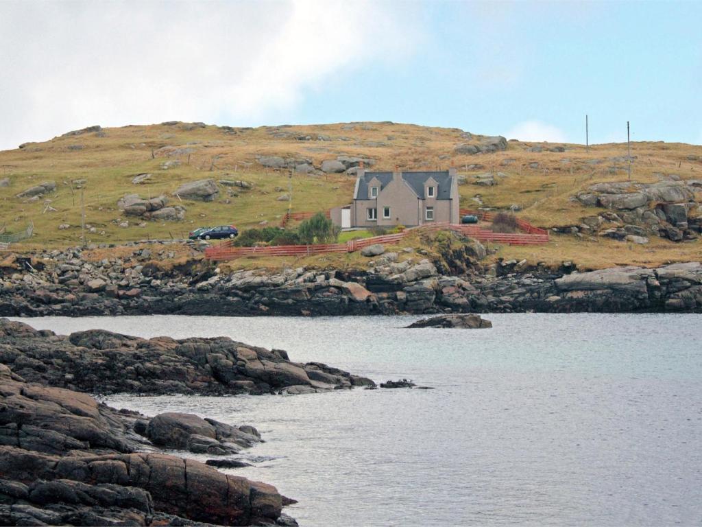 a house on top of a hill next to the water at 3 Bed in Isle of Barra CA295 in Ersary