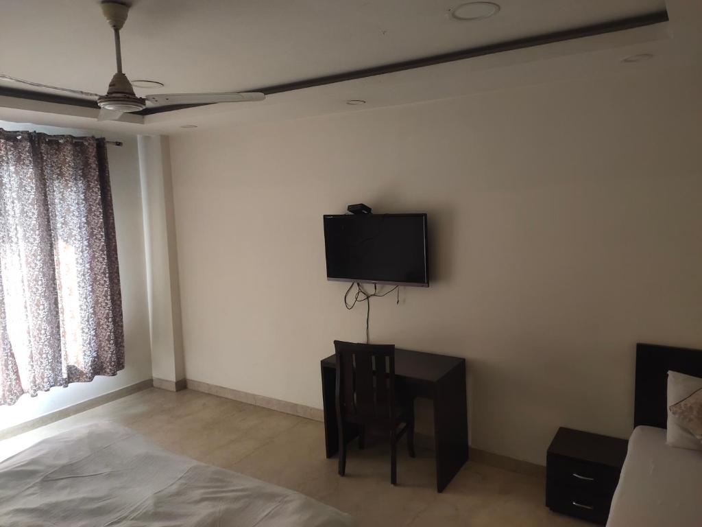a bedroom with a bed and a tv on the wall at A J RESIDENCE in New Delhi