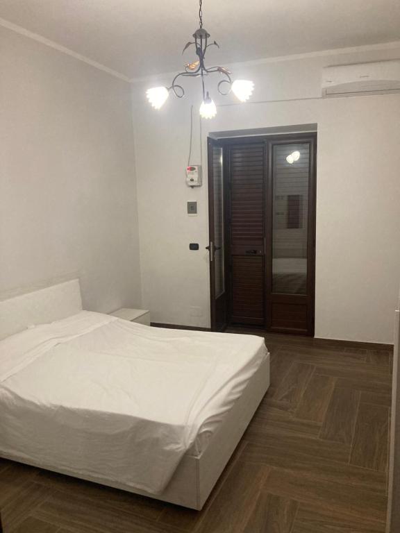- une chambre avec un lit blanc et du parquet dans l'établissement Trotskyhouse, à Campobello di Licata