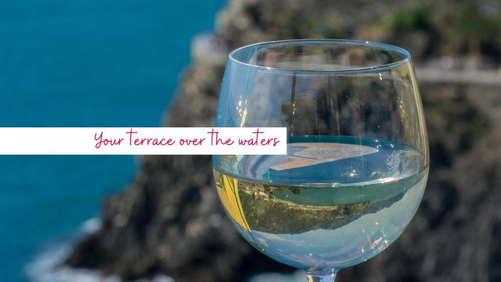 a glass of wine with a sign that reads your senses over the water at La Lampara Sea View Terrace Apartment in Manarola