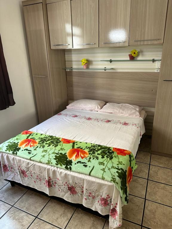 um pequeno quarto com uma cama com colcha floral em Apartamento Sol da Praia do Morro em Guarapari