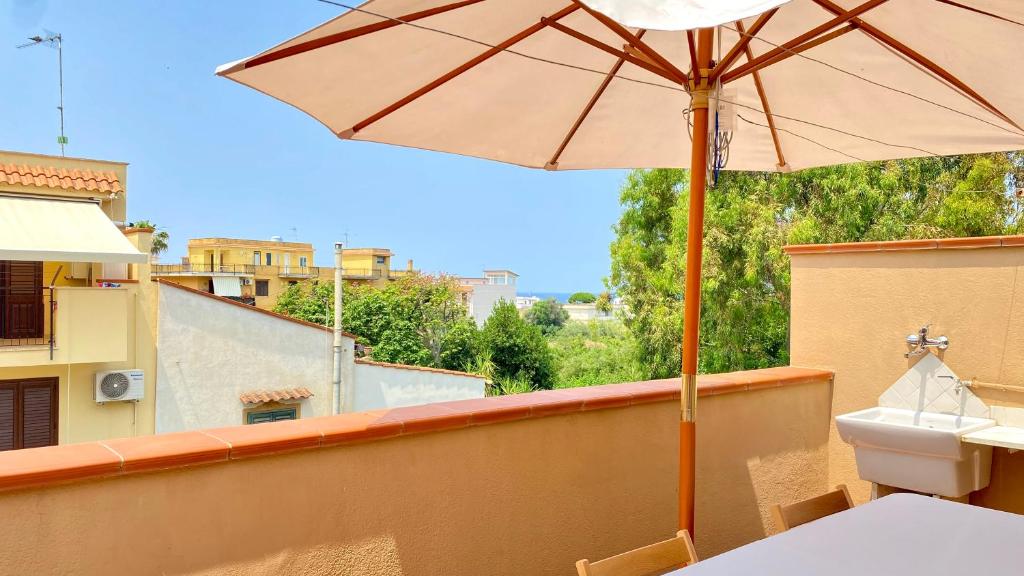 uma varanda com um guarda-chuva, uma mesa e um WC em Casa Giusy em Terrasini