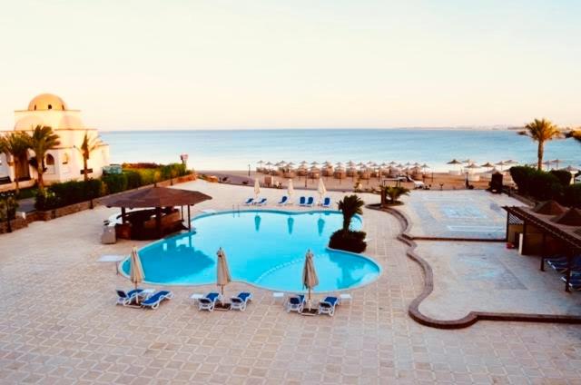 a large swimming pool with chairs and umbrellas at Apartment Sahl Hasheesh 1+1 in Hurghada