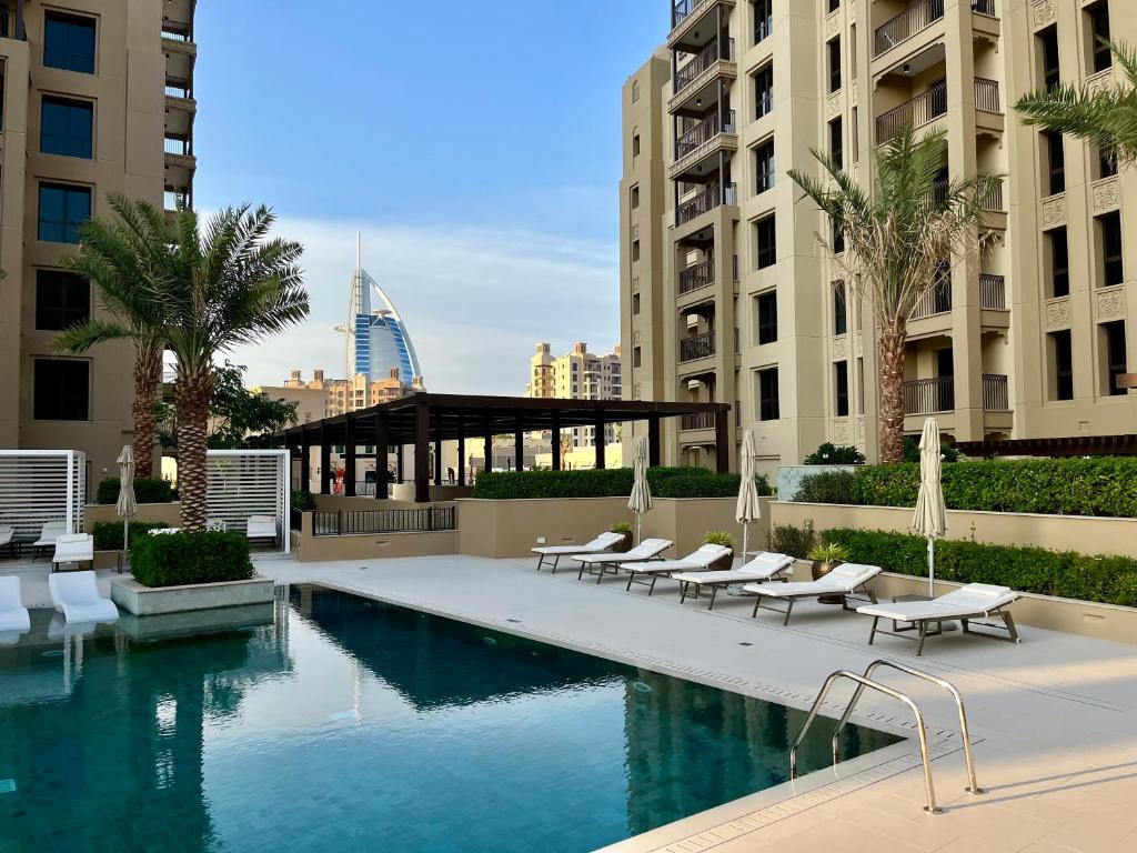 a swimming pool with lounge chairs and a building at New 2 bedroom entire apartment in Madinat Jumeirah Living in Dubai