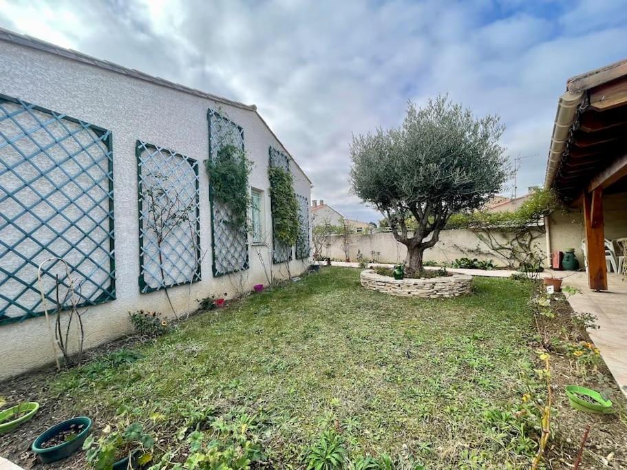 un bâtiment avec des fenêtres et un arbre dans une cour dans l'établissement Villa Anatole - parking privé - 900m Cité Médiévale, à Carcassonne