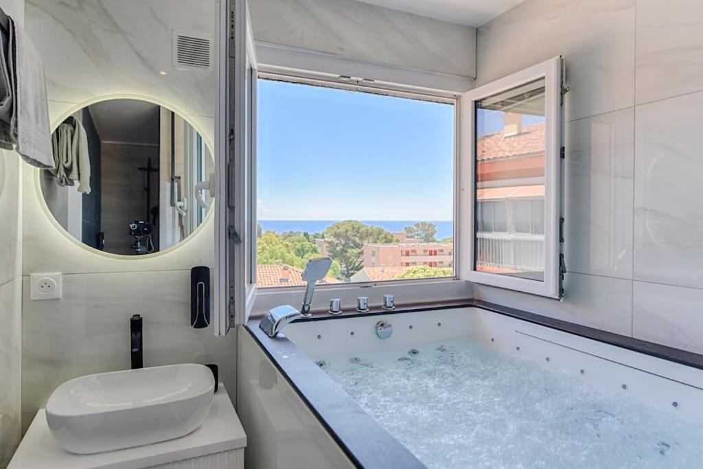uma casa de banho com uma banheira, um WC e uma janela. em Sea view & spa suite: 3min beach em Fréjus