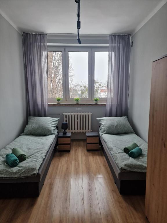 two beds in a room with two windows at CZARNA PERŁA in Wrocław