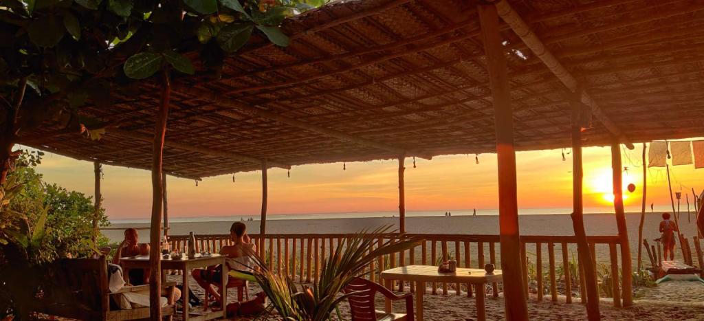 a sunset on the beach with people sitting at tables at Kenchas Beach Resort in Gokarna