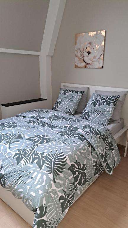 1 cama con edredón y almohadas azules y blancos en chambre cocooning, en Annappes