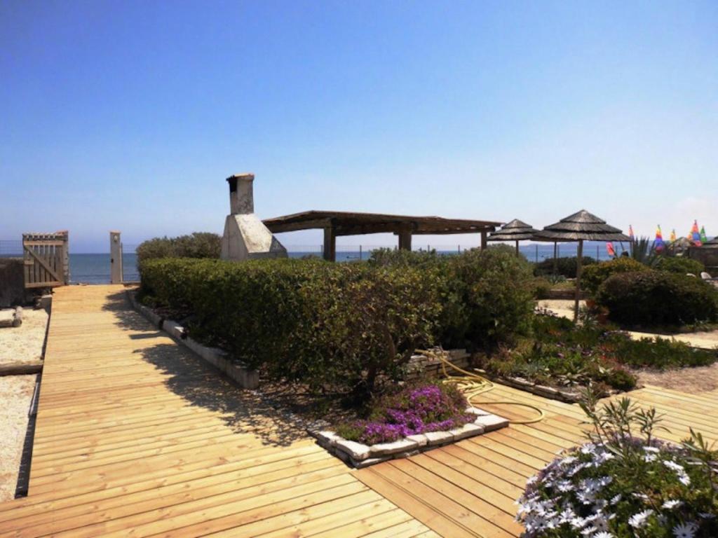 - une terrasse en bois avec des plantes et des fleurs sur la plage dans l'établissement Au Grand sud, à Hyères