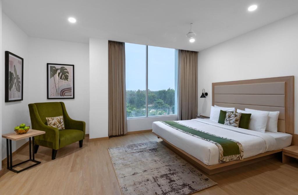 - une chambre avec un grand lit et une chaise verte dans l'établissement Lemon Tree Hotel, Vadodara, à Vadodara