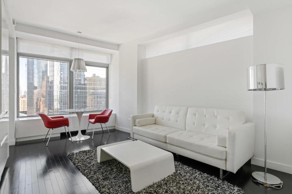 uma sala de estar branca com um sofá branco e cadeiras vermelhas em Financial District 1br w WD gym elevator NYC-1368 em Nova York