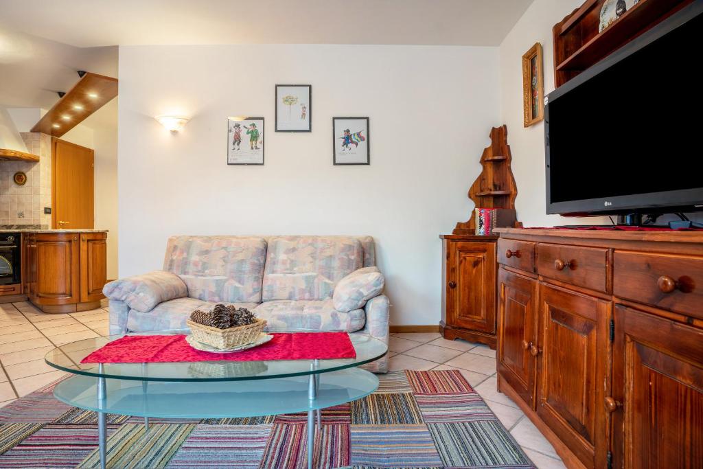 sala de estar con silla, mesa y TV en Casa al portico Val di Cembra en Grauno