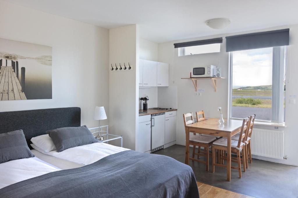 a bedroom with a bed and a table and a kitchen at South Central Apartments in Brautarholt