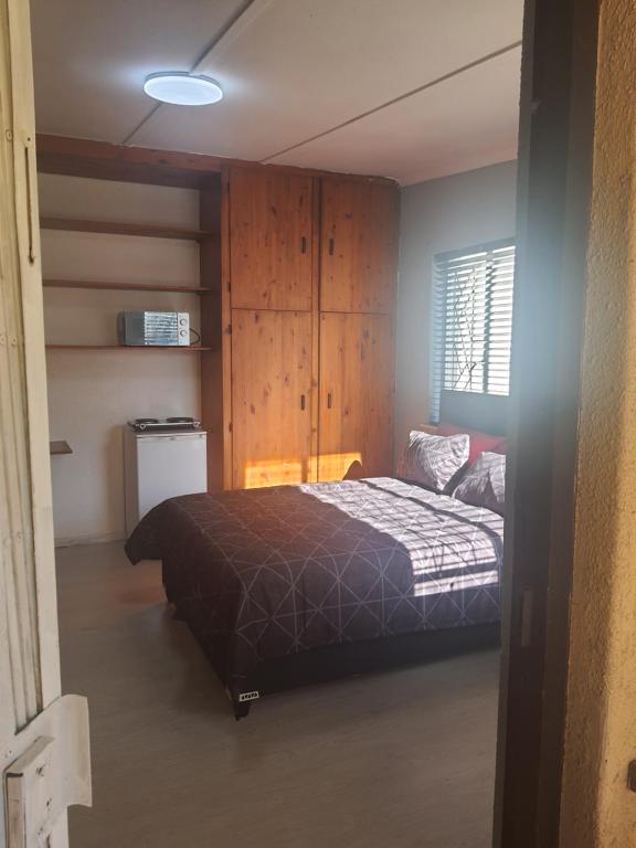 a bedroom with a bed in a room with wooden cabinets at Thornton room in Cape Town