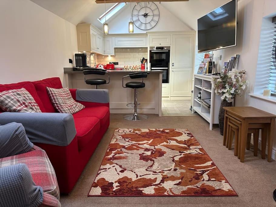 a living room with a red couch and a kitchen at The Nest, lovely apartment in Holt