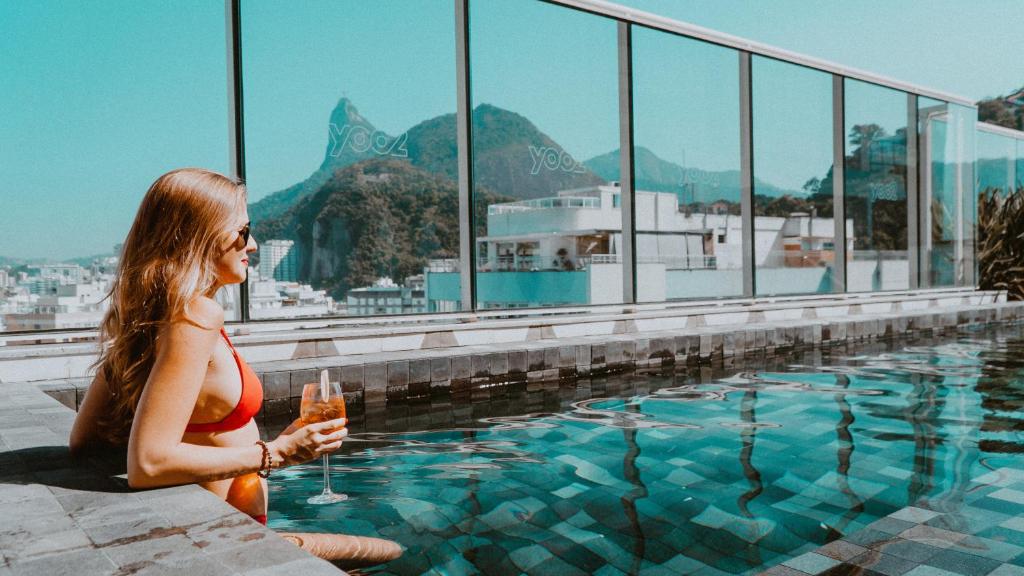 Eine Frau in einem roten Bikini sitzt neben einem Pool. in der Unterkunft Yoo2 Rio de Janeiro by Intercity in Rio de Janeiro