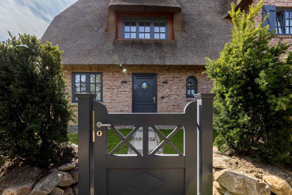 a gate in front of a house with a thatched roof at Sunrise-Beach in Wenningstedt