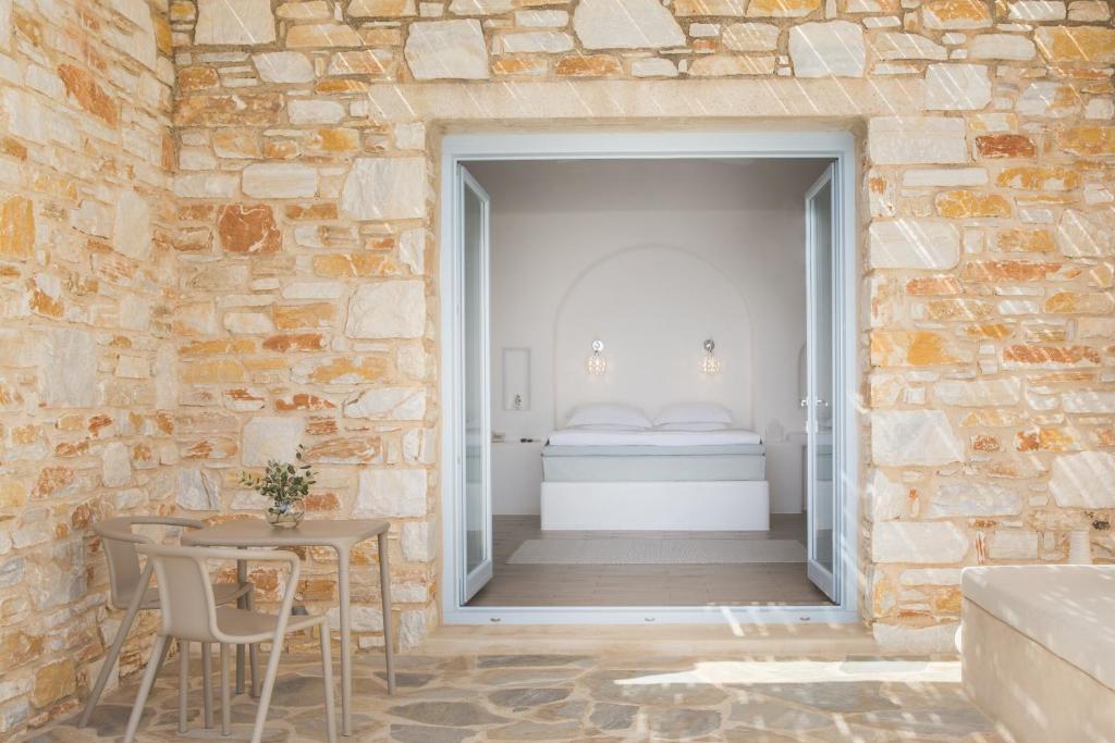 Cette chambre dispose d'un mur en pierre, d'une table et d'un lit. dans l'établissement Calme Boutique Hotel - Adults Only, à Drios