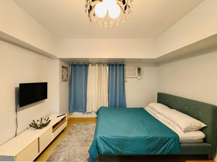 Schlafzimmer mit einem Bett, einem TV und einem Kronleuchter in der Unterkunft A2* * Uptown Retreat in Iloilo City